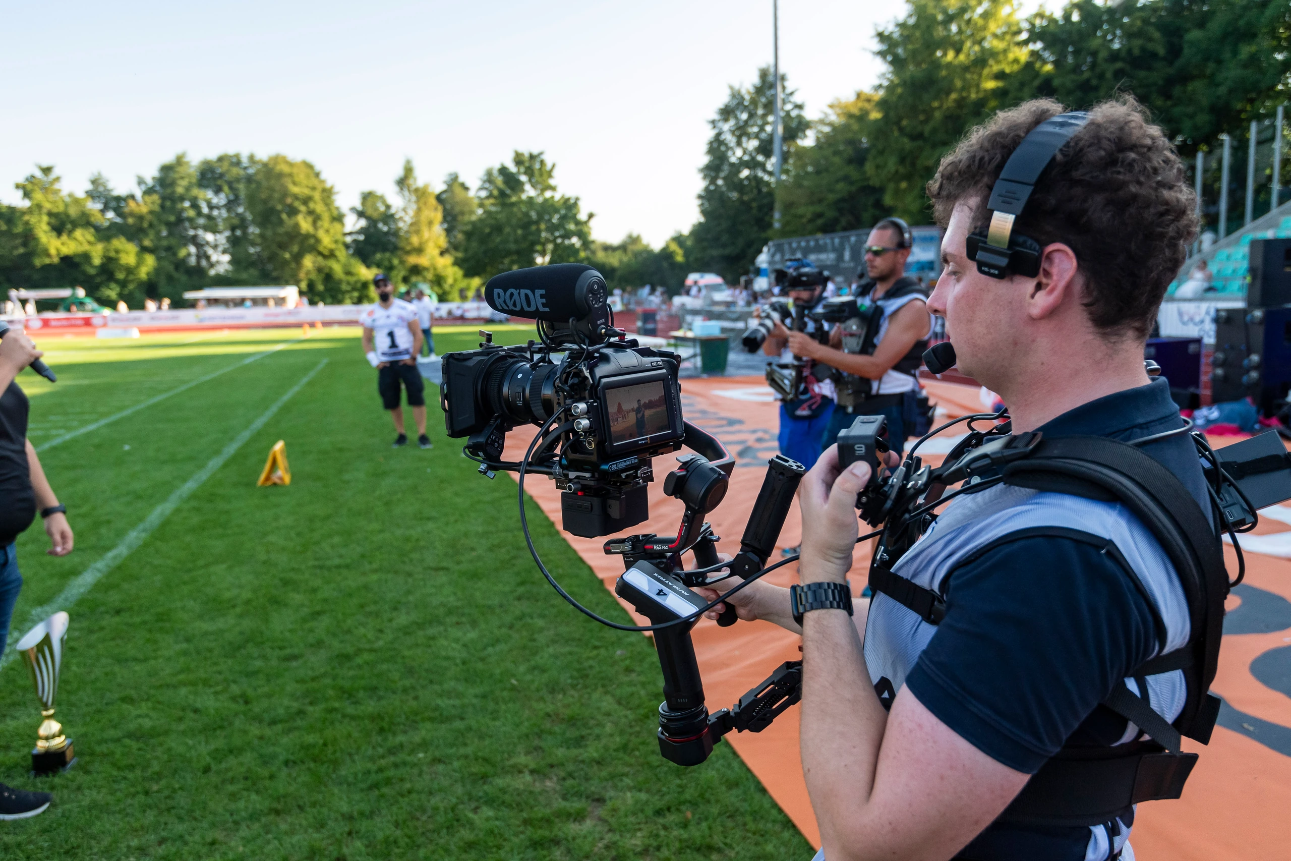 Kameramann am Spielfeldrand mit Blackmagic-Kamera auf dem Gimbal und Headset während einer Live-Produktion